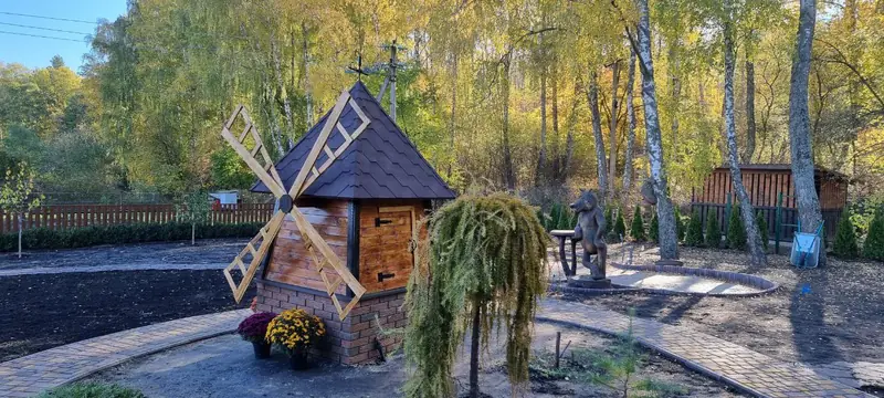 Декоративний млин, квіти й плакуча модрина на доглянутій ділянці